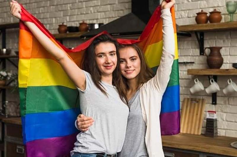 Two girls holding rainbow flag