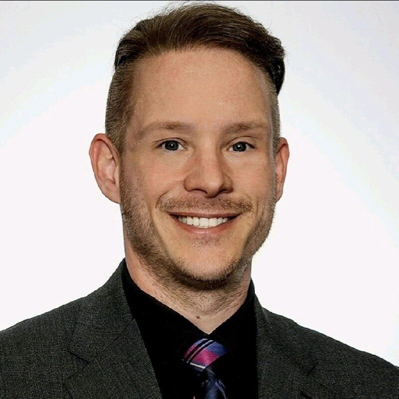 A smiling man wearing a suit and tie with a clean white background.